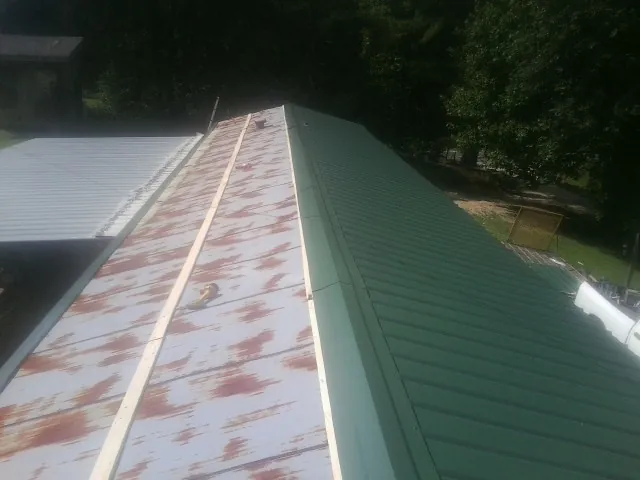 Old rusted panels beside newly installed green metal roofing — Wind Damage Roof Repair by Roofing Brothers in Greenleaf