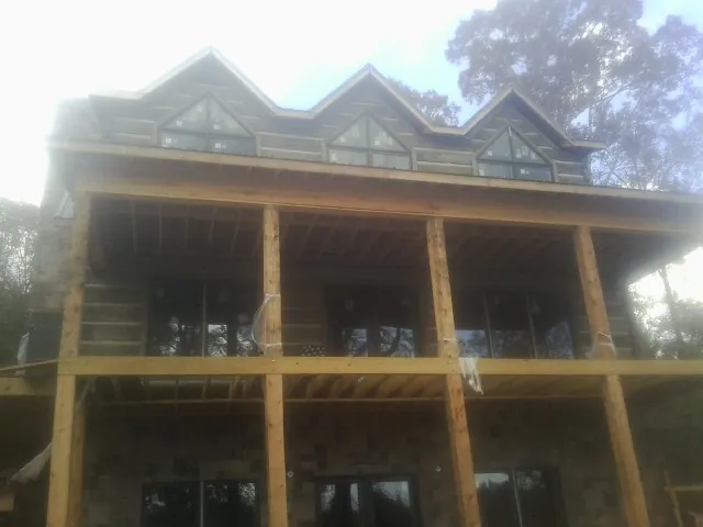 Dormers and porch framing on a large log home under construction — Roof Coating work by our crew in Greenleaf