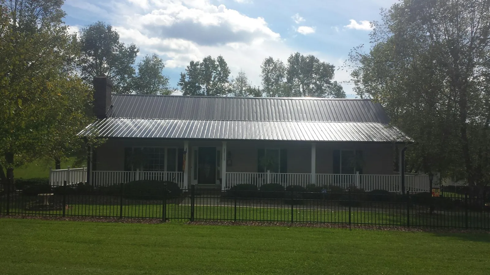 Gray metal roof on a brick ranch with a full width front porch — Gutter Guard Installation work by our crew in Greenleaf